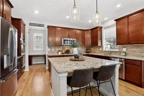 a kitchen with granite countertop kitchen island stainless steel appliances a sink stove and refrigerator