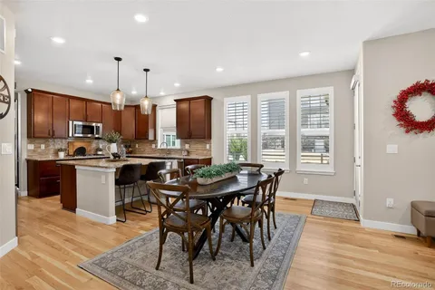 a kitchen with stainless steel appliances granite countertop a stove a refrigerator a kitchen island a table and chairs