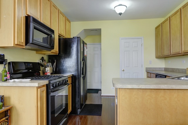 565 Springbrook Trail North Oswego, IL 60543 - Photo 13 of 21 a kitchen with stainless steel appliances granite countertop a stove top oven a refrigerator a sink and dishwasher with wooden floor