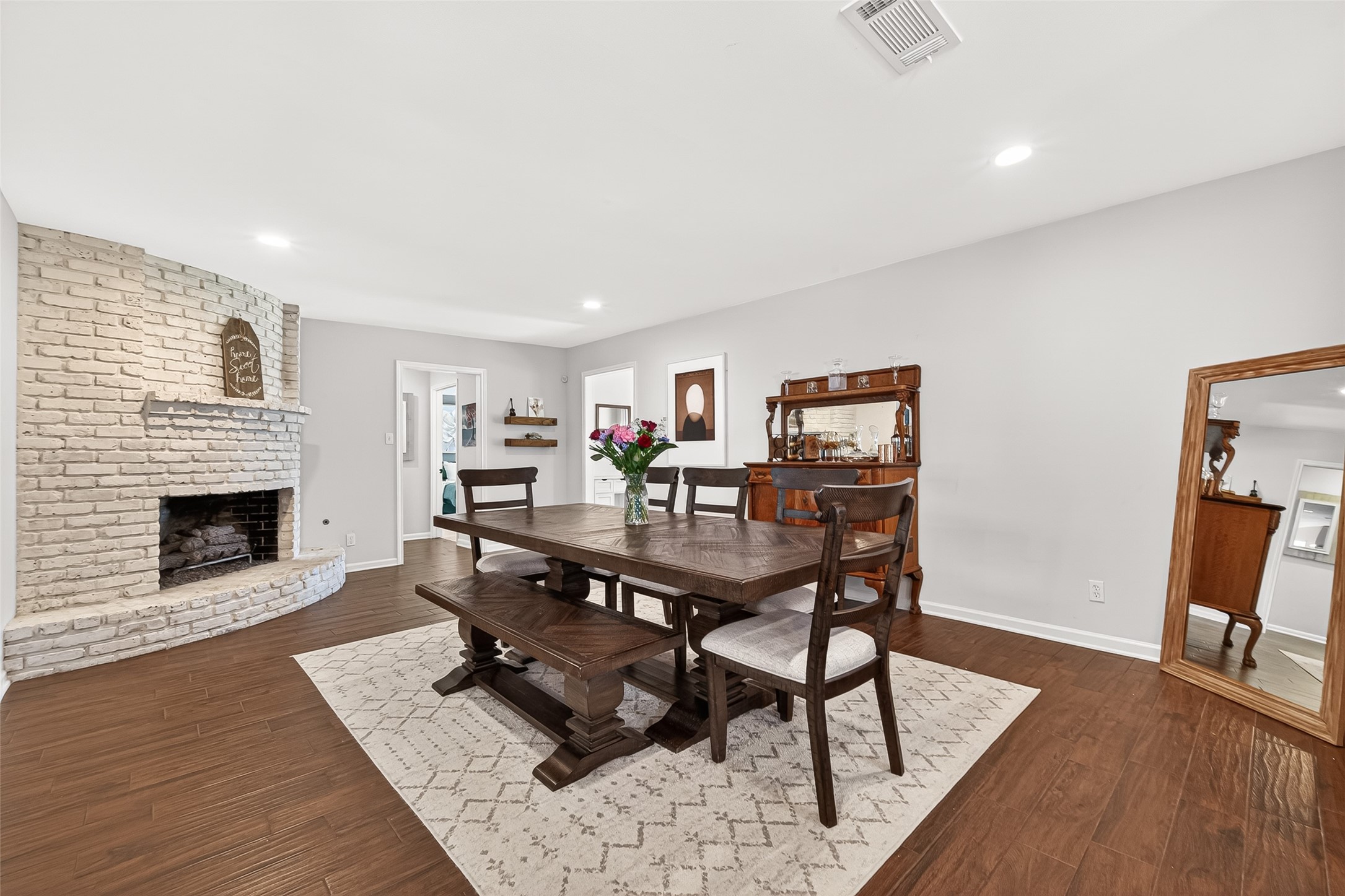 2610 Teague Road Houston, TX 77080 - Photo 5 of 49 This inviting dining room features a cozy white brick fireplace, and beautiful wood-like tile floors. It offers a warm and welcoming atmosphere, perfect for family gatherings.