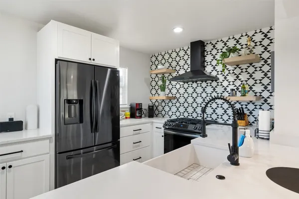 a kitchen with granite countertop a refrigerator and a stove top oven