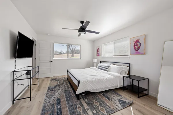 a bedroom with a bed a flat tv screen and a dresser