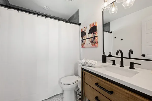 a bathroom with a granite countertop sink a toilet and a shower curtain