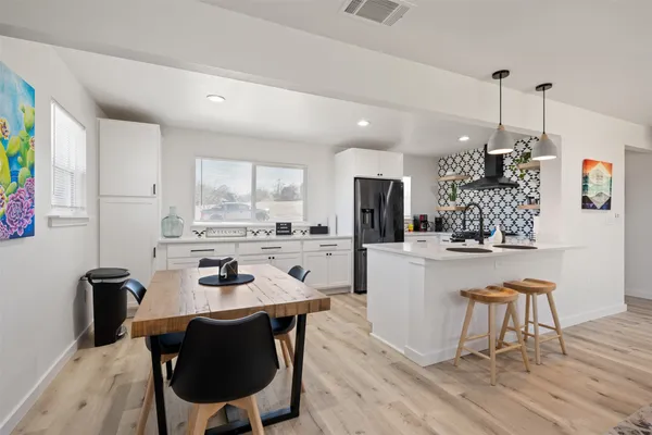 a kitchen with a dining table chairs and refrigerator