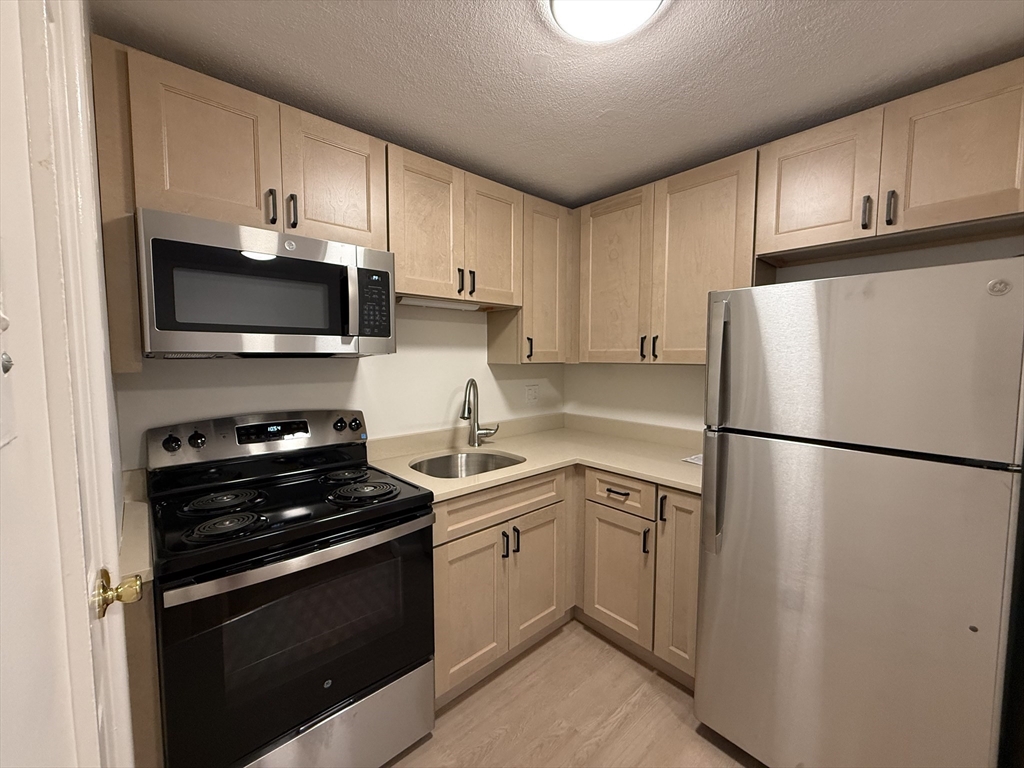 a white kitchen with sink a microwave and refrigerator