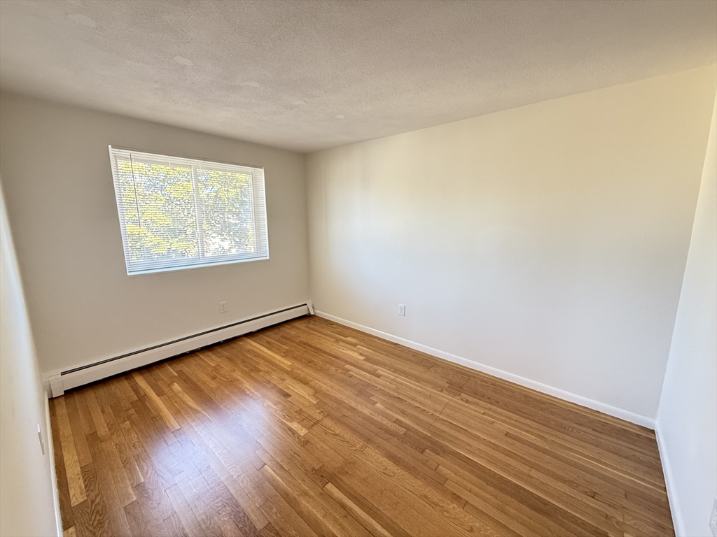 154 Main Street, Unit 32 Everett, MA 02149 - Photo 5 of 10 an empty room with wooden floor and windows