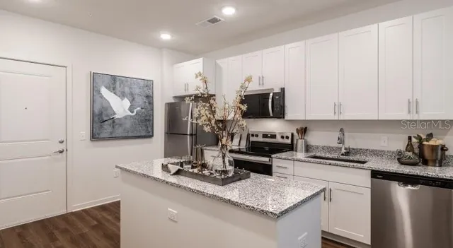 a kitchen with stainless steel appliances granite countertop a sink stove refrigerator and cabinets