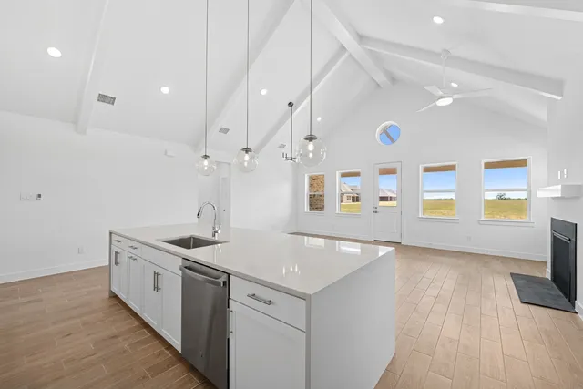 a kitchen with stainless steel appliances granite countertop a sink a stove and a wooden floors