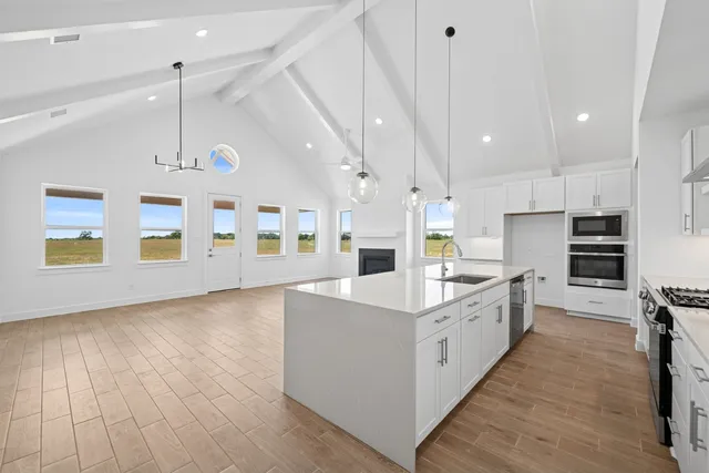 a large white kitchen with lots of counter space a sink appliances and cabinets