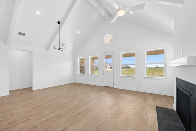a view of an empty room with a window and wooden floor