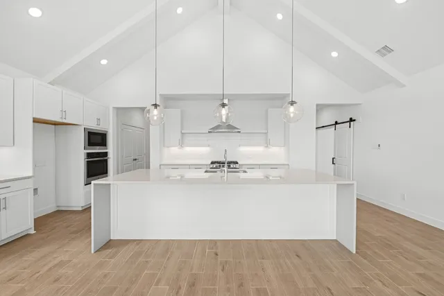 a large room with kitchen island a stove a refrigerator and a wooden floor