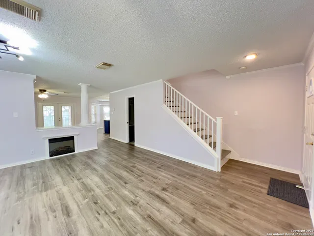 a view of empty room with wooden floor and fan