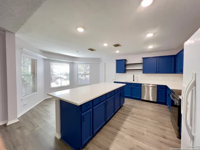 a kitchen with stainless steel appliances kitchen island granite countertop wooden cabinets and sink