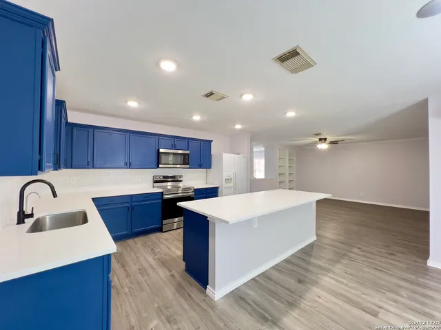 a large kitchen with kitchen island a sink a stove and a wooden floors