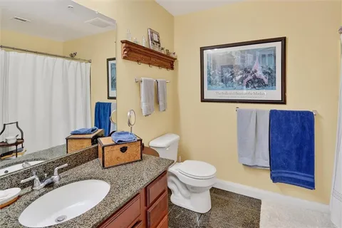 a bathroom with a granite countertop sink mirror vanity and toilet