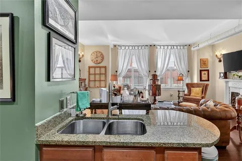 a kitchen with a sink a counter top space and living room view