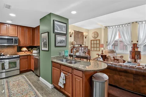 a kitchen with stainless steel appliances granite countertop a sink a stove and a refrigerator