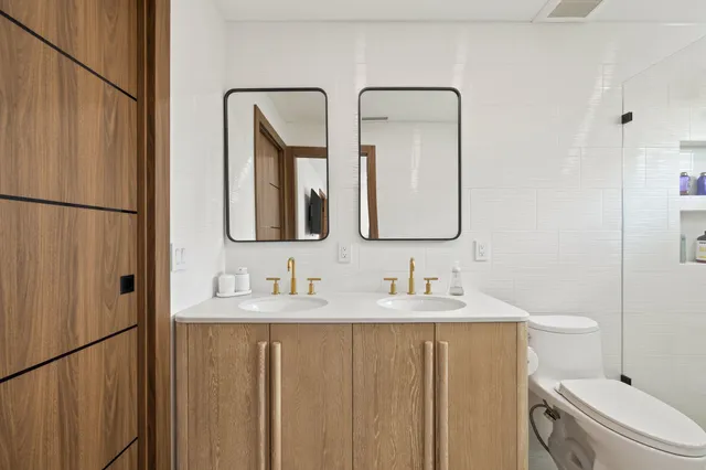 a bathroom with 2 sink toilet and shower