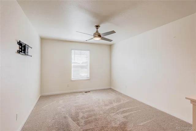 an empty room with a window and a ceiling fan