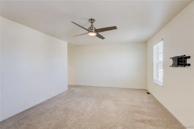 an empty room with a window and a ceiling fan