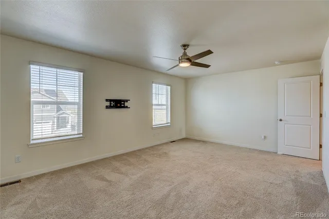 an empty room with windows and ceiling fan
