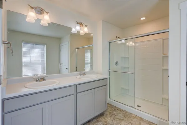 a bathroom with a double vanity sink mirror and shower