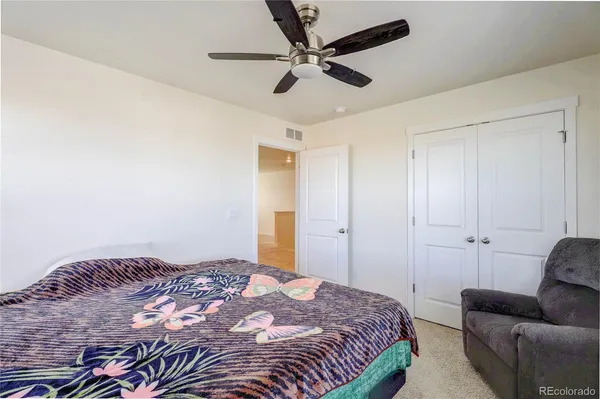 a bedroom with a bed couch and a ceiling fan