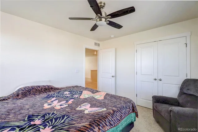 a bedroom with a bed couch and a ceiling fan