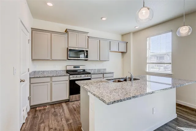 a kitchen with granite countertop a stove sink and microwave