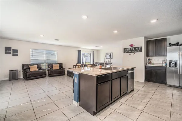 a large white kitchen with a stove a sink a couch and a refrigerator