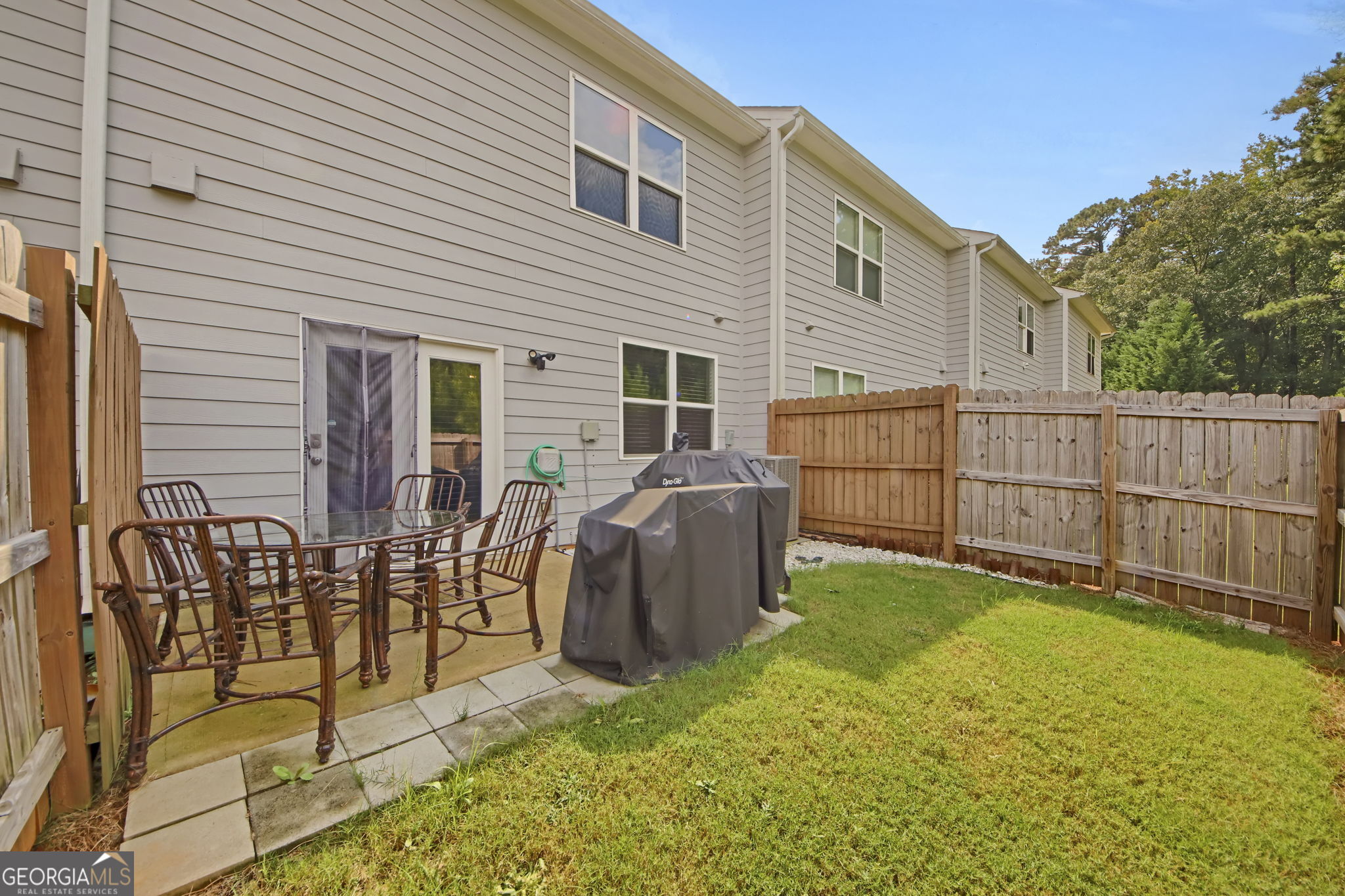 11924 Fuller Street Hampton, GA 30228 - Photo 24 of 26 a view of a backyard with table and chairs potted plants and wooden fence