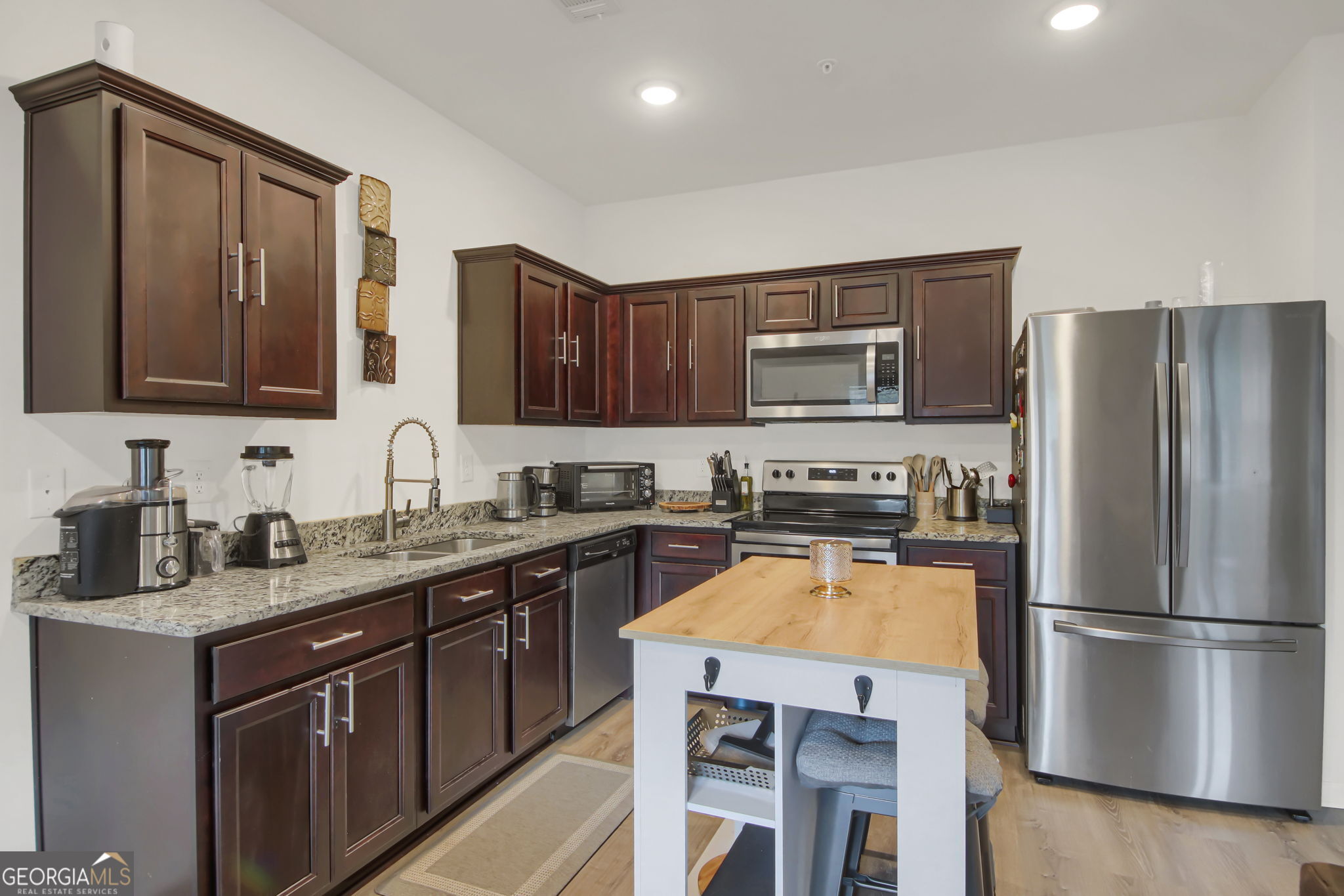 11924 Fuller Street Hampton, GA 30228 - Photo 10 of 26 a kitchen with a refrigerator a microwave a sink and cabinets