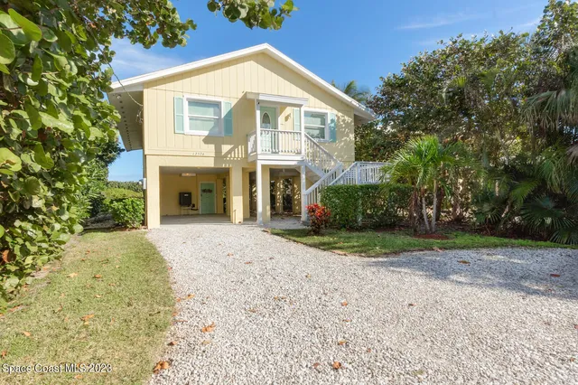 a view of a house with a yard and potted plants