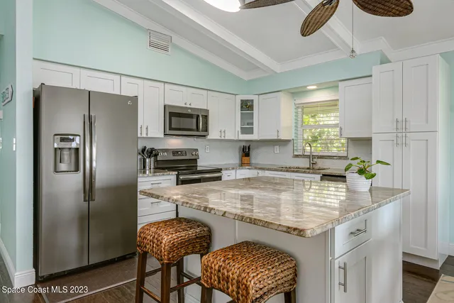 a kitchen with stainless steel appliances granite countertop a sink a stove a refrigerator a microwave cabinets and a dining table