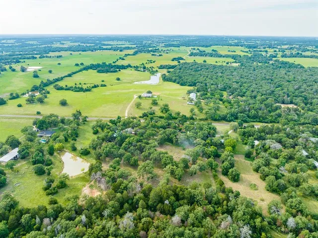 an aerial view of residential houses with outdoor space and trees
