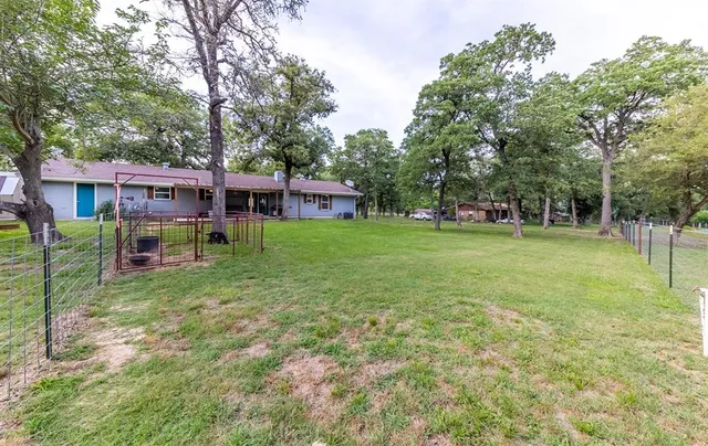 a view of a house with a big yard and large trees