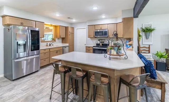 a kitchen with stainless steel appliances a table chairs refrigerator and microwave