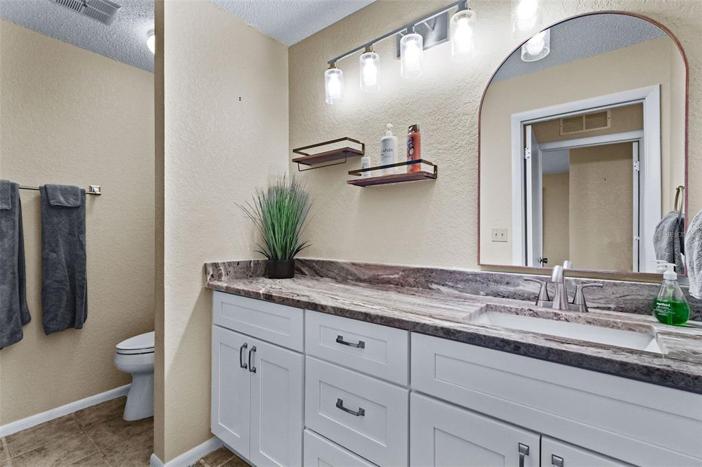 1417 Heather Ridge Boulevard Dunedin, FL 34698 - Photo 22 of 37 a bathroom with a granite countertop sink a toilet and mirror