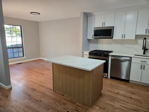 a kitchen with stainless steel appliances a stove top oven a sink a refrigerator and cabinets