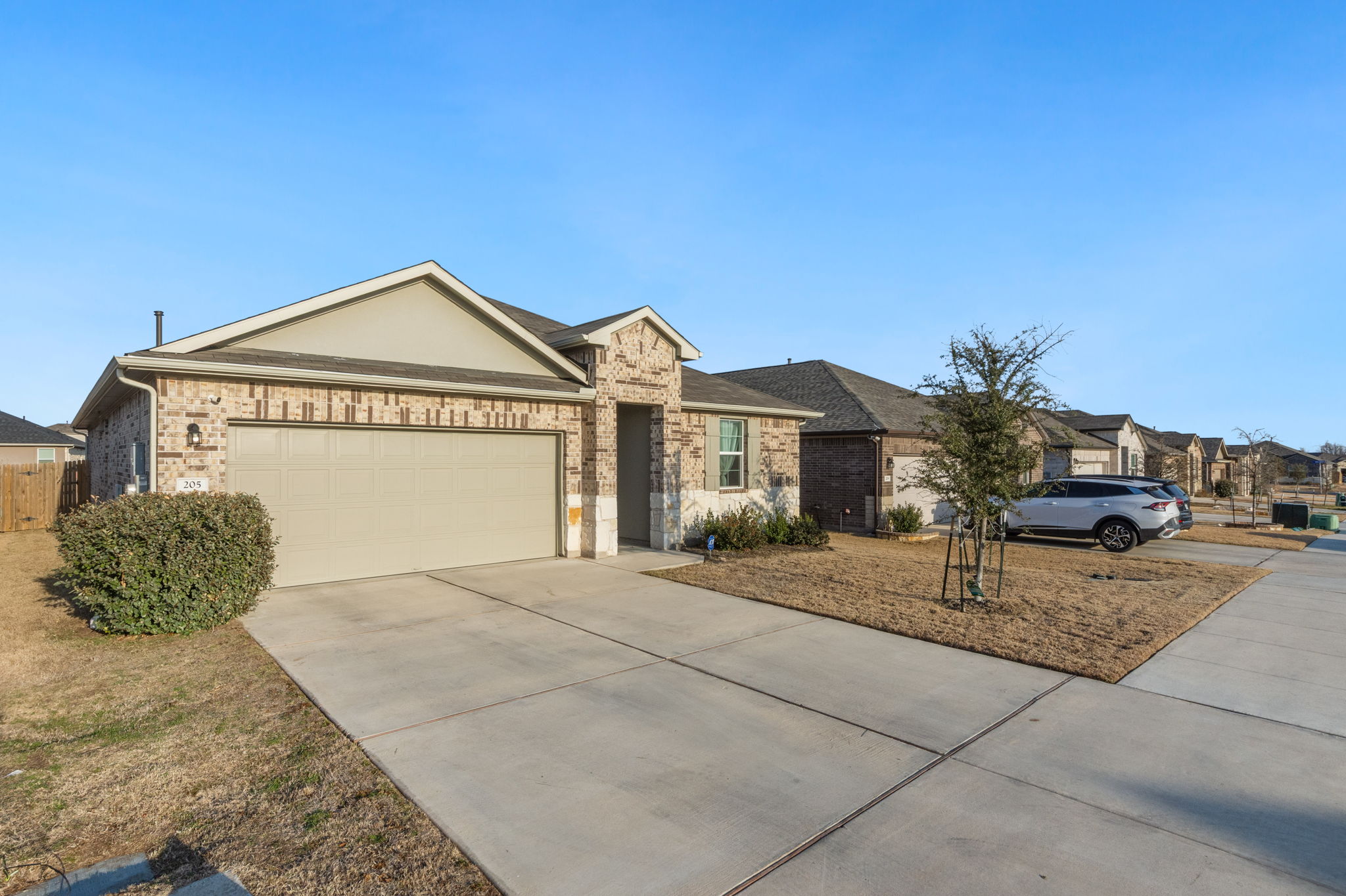 205 Charles Trail Georgetown, TX 78626 - Photo 7 of 36 Single story home with concrete driveway, a garage, brick siding, and a residential view