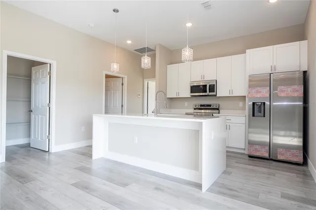 a kitchen with stainless steel appliances a stove a refrigerator and a microwave