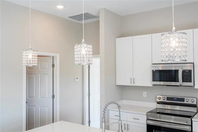 a kitchen with stainless steel appliances granite countertop a stove top oven a sink dishwasher and white cabinets with wooden floor