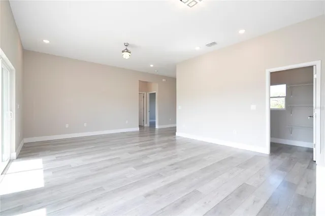 a view of an empty room with wooden floor and a floor to ceiling window