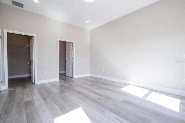 an empty room with wooden floor and natural light