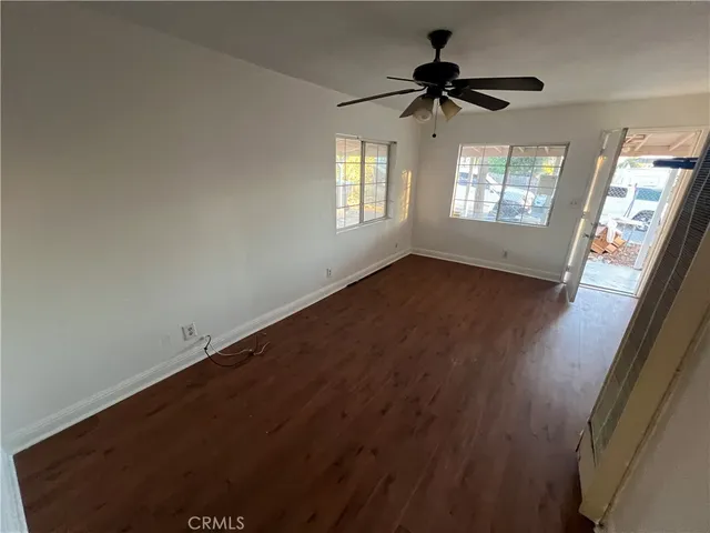 a view of empty room with wooden floor and fan