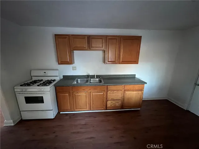 a kitchen with granite countertop a stove and a wooden floors