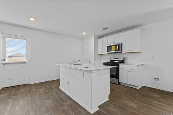 a kitchen with cabinets stainless steel appliances and wooden floor