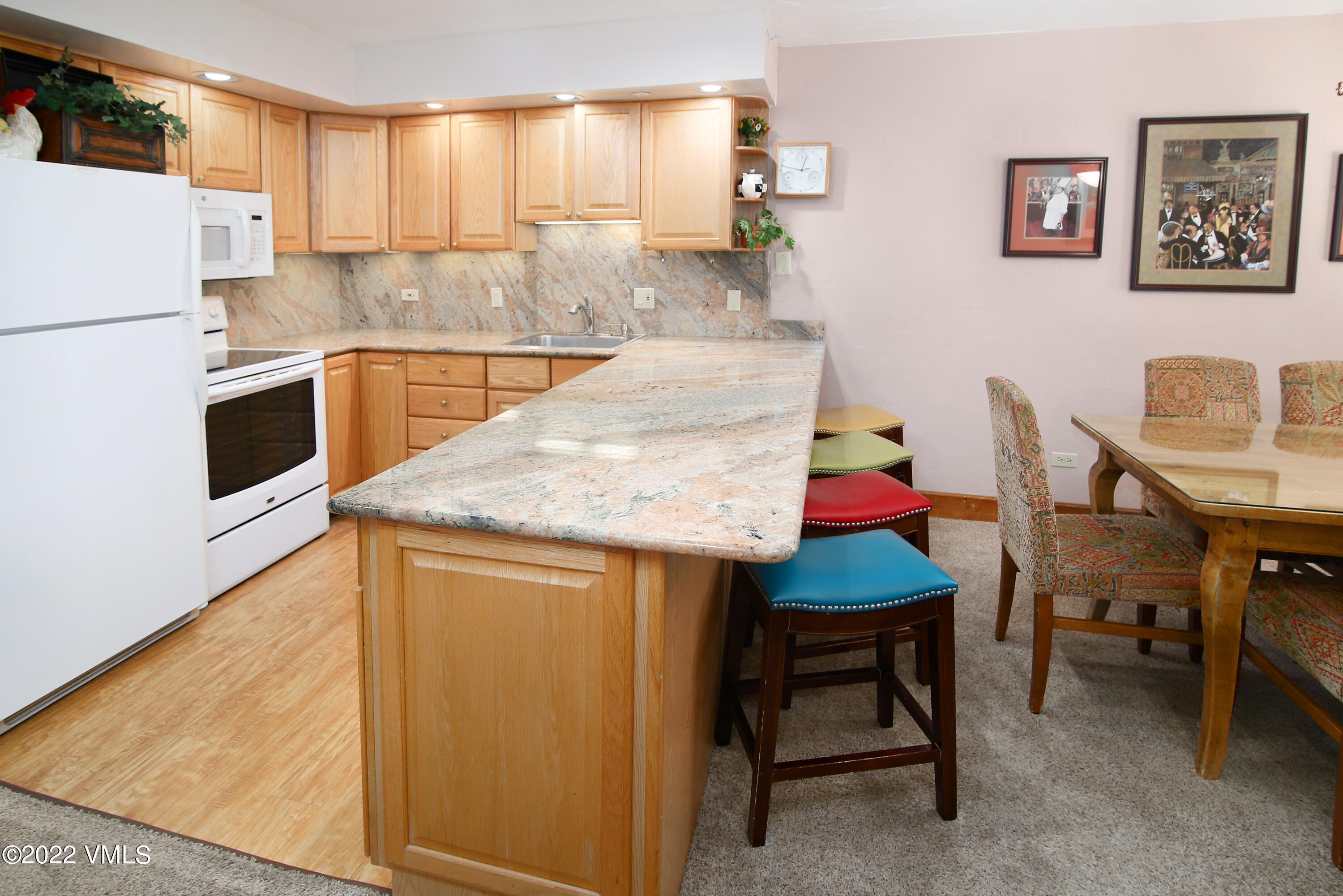 548 South Frontage Road West, Unit 105 Vail, CO 81657 - Photo 4 of 19 a kitchen with stainless steel appliances granite countertop a table chairs sink and white cabinets