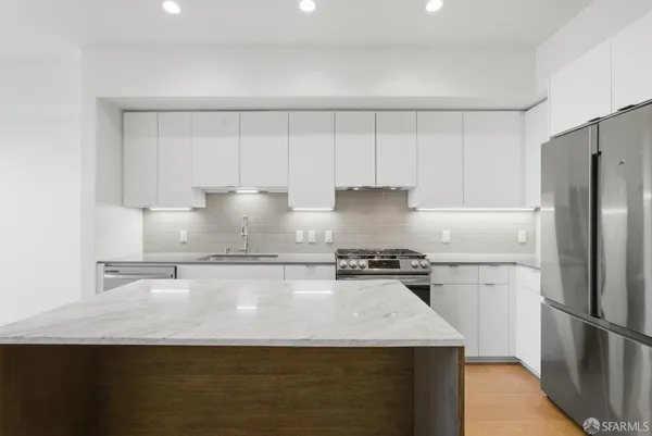 a view of a kitchen with refrigerator and white cabinets