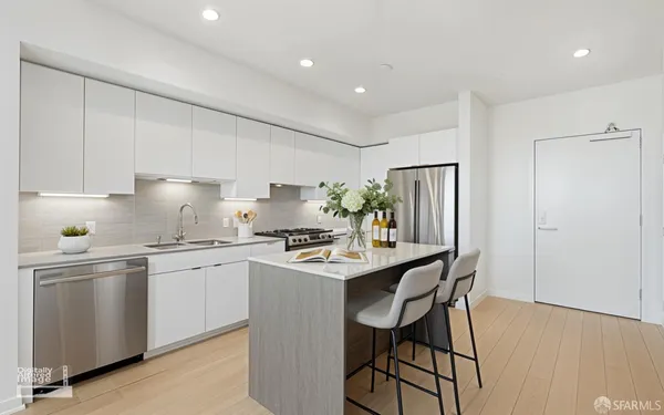 a kitchen with stainless steel appliances a table chairs refrigerator and wooden cabinets